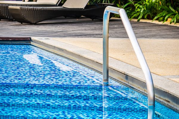 Beautiful outdoor swimming pool with bed deck chair and umbrella in resort for travel and vacation concept